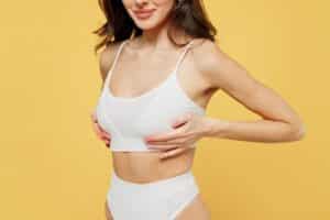 side view of young woman in white brassiere underwear put hand on chest