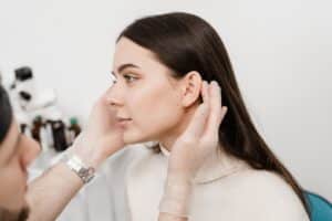 Woman having her ears evaluated for reparative earlobe surgery