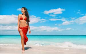 Woman on beach with nicely toned body thanks to liposuction