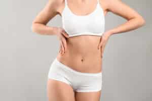 Close up of woman's abdomen with toned body after liposuction