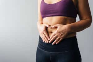 Woman holding hands in heart shape over her abdomen.