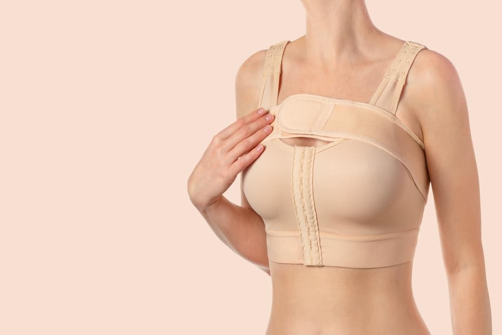 Woman in compression bra to promote healing and minimize scars after breast surgery