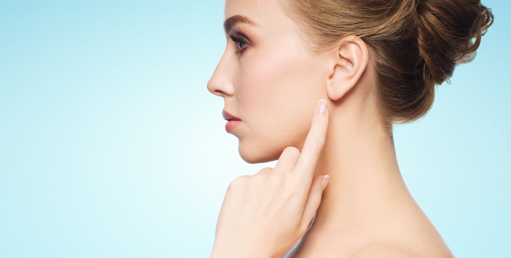 Woman pointing to her earlobe after scar revision treatment