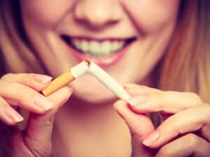 Woman smiling and breaking a cigarette in half to signify quitting