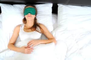 Woman lying on back to sleep and wearing eye mask