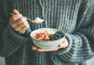 Woman in sweater eating health bowl full of nutritious foods